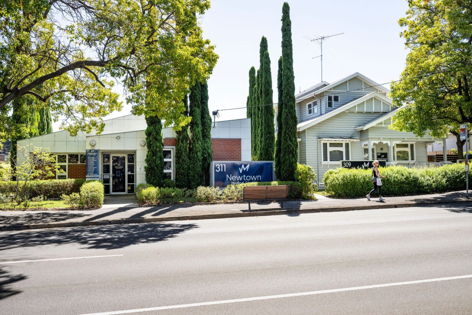 Photograph of the outside of a clinic taken across the road with pine trees out the front